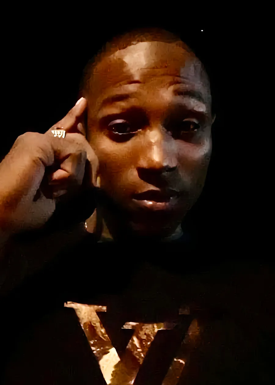 Missionary KD, lit in gold against a black background, one finger raised to his temple